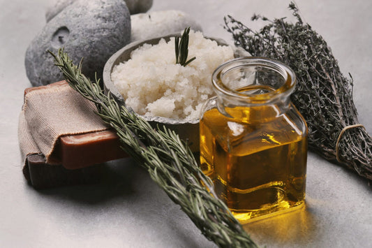 Rosemary olive oil, salt scrub and stones displayed on marble counter