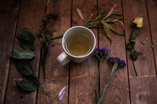 Cup of green tea on wooden table with a variety of flowers on the table